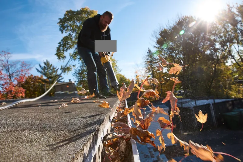 Gutter cleaning — clearing autumn leaves from an eavestrough